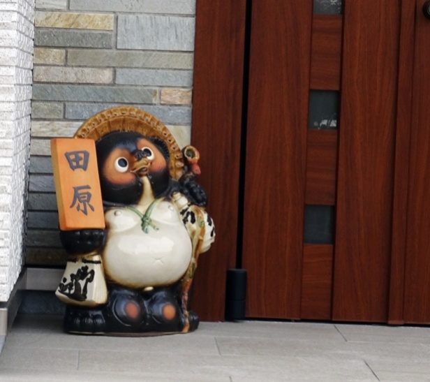 Ein Tanuki vor einer Haustür